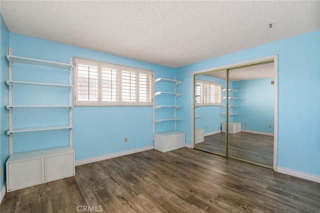 unfurnished bedroom with baseboards, wood finished floors, a closet, and a textured ceiling