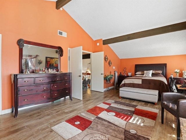 bedroom featuring wood finished floors, visible vents, baseboards, high vaulted ceiling, and beam ceiling