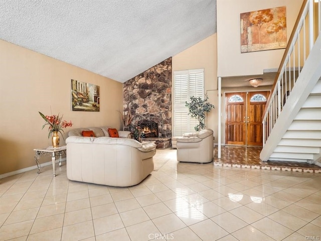 living room featuring light tile patterned flooring, a stone fireplace, a textured ceiling, and stairs