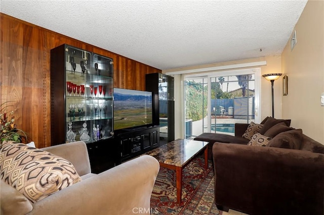 living area with visible vents, wood walls, and a textured ceiling