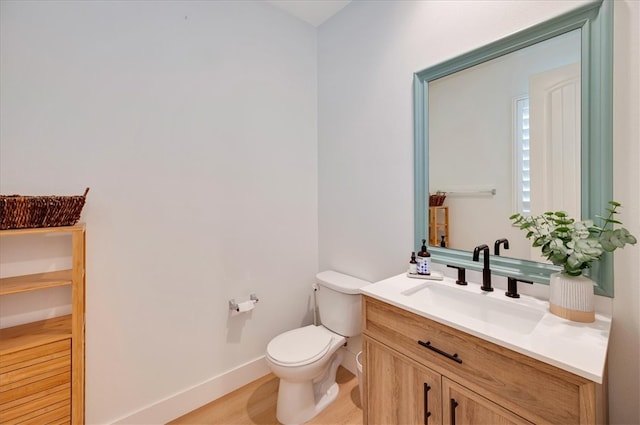 bathroom featuring baseboards, toilet, wood finished floors, and vanity