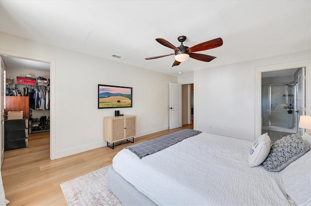 bedroom with visible vents, a walk in closet, baseboards, light wood-type flooring, and a closet