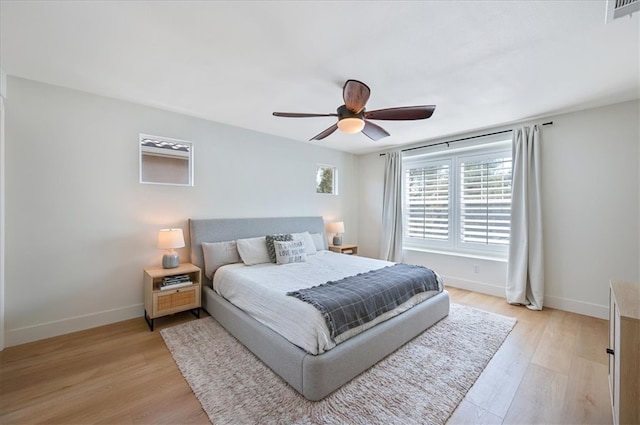 bedroom featuring a ceiling fan, visible vents, light wood-type flooring, and baseboards