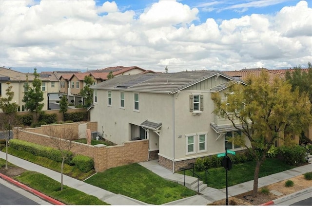 exterior space with a residential view, stucco siding, a tile roof, and a yard