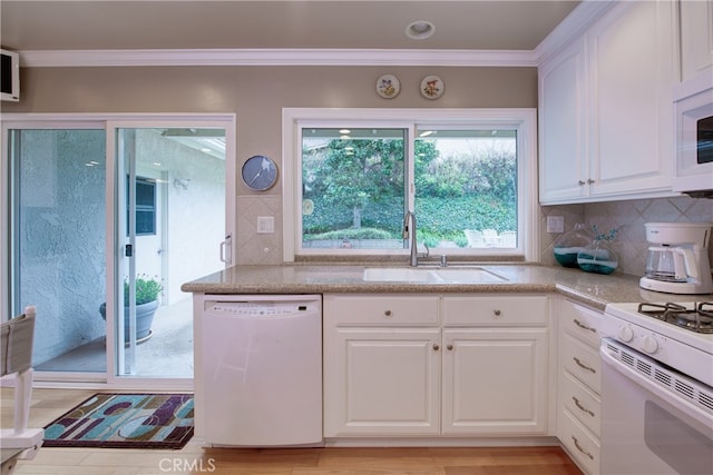 kitchen with white appliances, a sink, decorative backsplash, white cabinetry, and crown molding