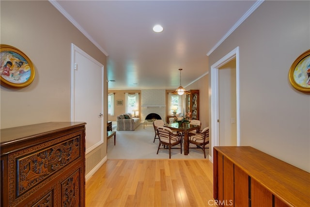 corridor with light wood-style flooring and crown molding