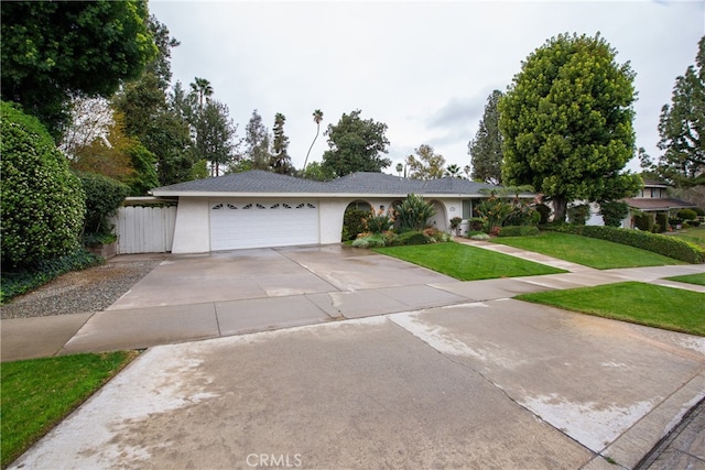 ranch-style home with stucco siding, driveway, fence, a front yard, and a garage