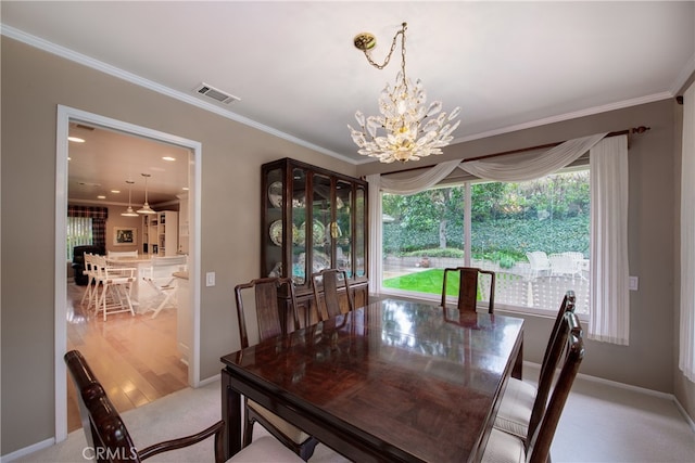 dining space with visible vents, wood finished floors, crown molding, baseboards, and a chandelier