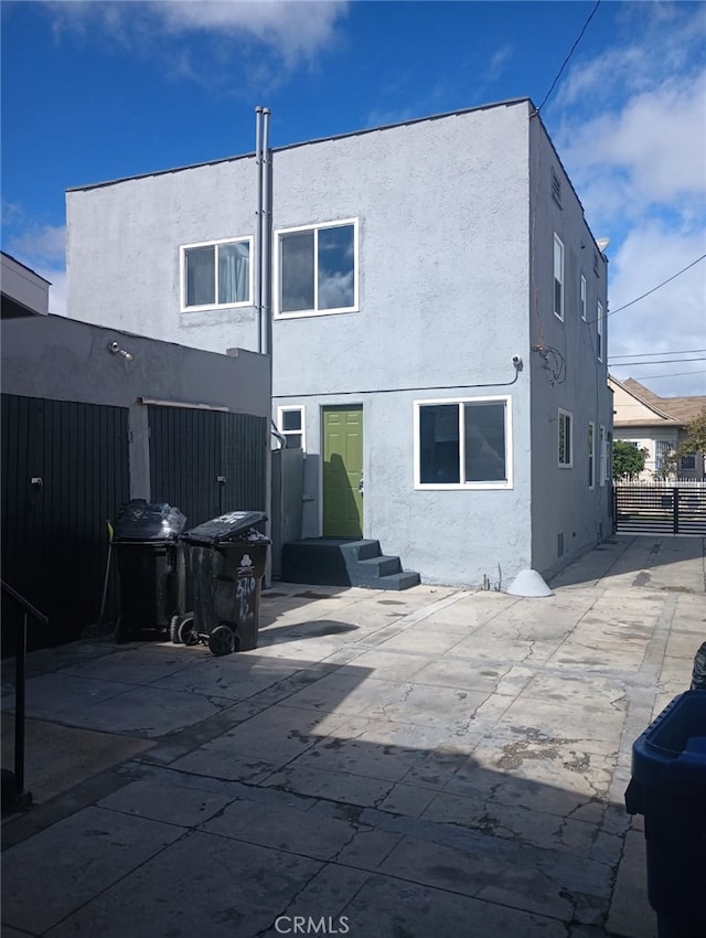 rear view of house featuring stucco siding, a patio area, entry steps, and fence