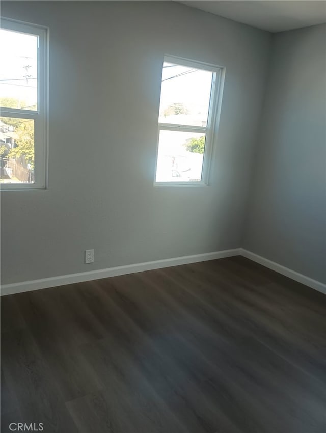 empty room with dark wood-type flooring and baseboards