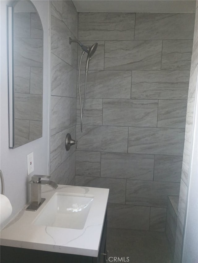 full bath with tiled shower and vanity