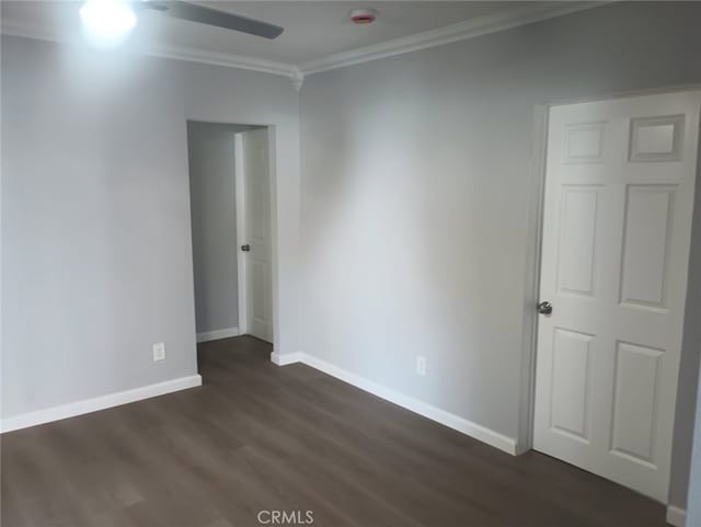 empty room featuring baseboards, a ceiling fan, dark wood-style flooring, and crown molding