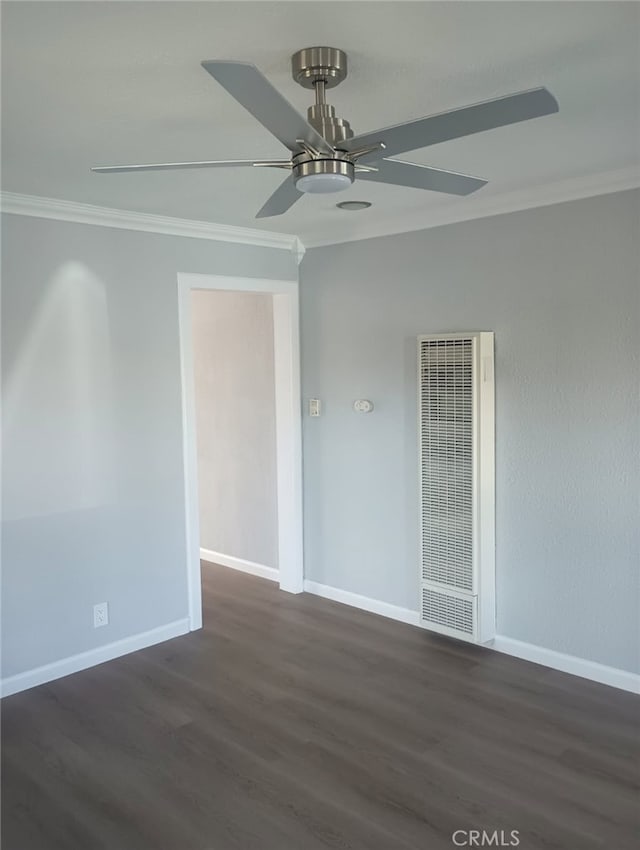 unfurnished room featuring a ceiling fan, dark wood-style floors, baseboards, a heating unit, and crown molding