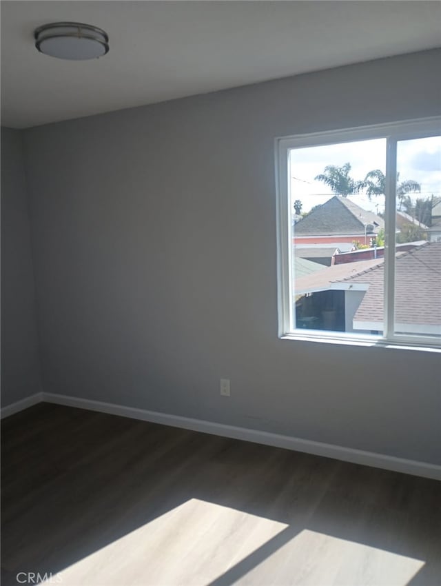 empty room featuring baseboards and dark wood-type flooring