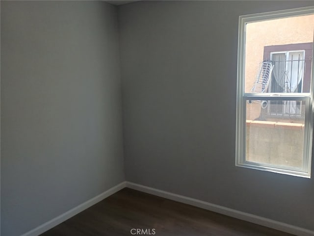 empty room with baseboards and dark wood-style flooring