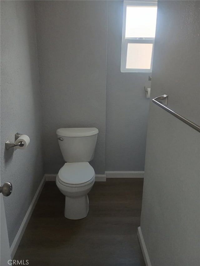 bathroom featuring toilet, wood finished floors, and baseboards