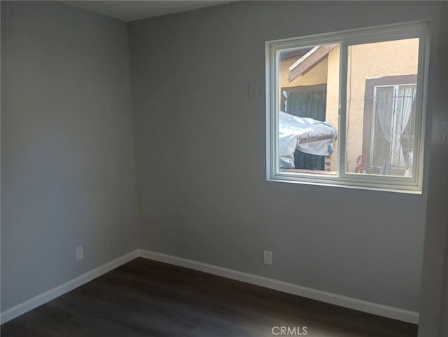 empty room with baseboards and dark wood-style floors