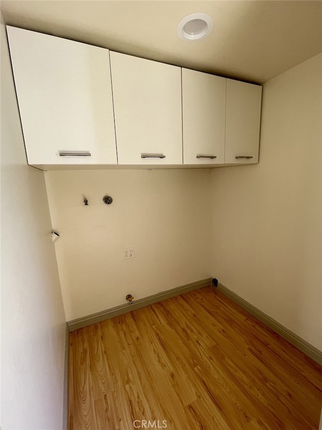 washroom with hookup for a washing machine, light wood-style flooring, cabinet space, and baseboards