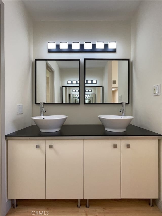 full bathroom with a sink, wood finished floors, and double vanity