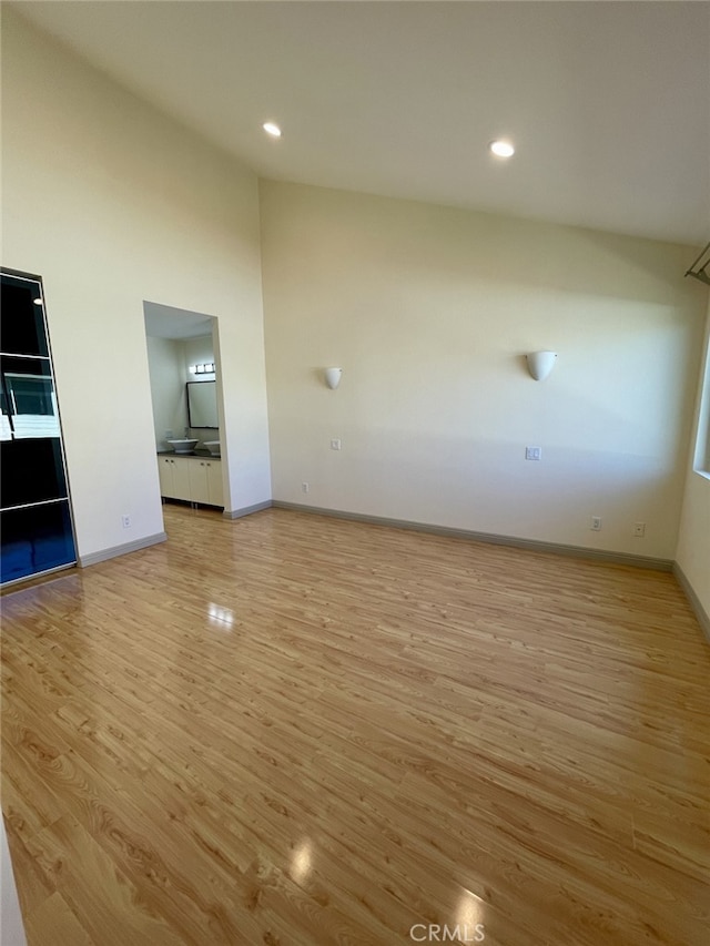 unfurnished room with recessed lighting, high vaulted ceiling, light wood-type flooring, and baseboards