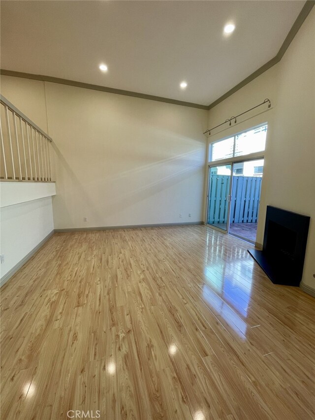 empty room with recessed lighting, baseboards, wood finished floors, and crown molding