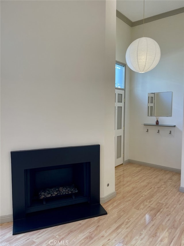 room details with wood finished floors, crown molding, a fireplace with raised hearth, and baseboards