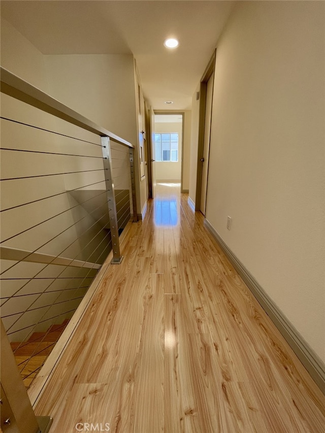 corridor featuring light wood-style flooring, recessed lighting, and baseboards