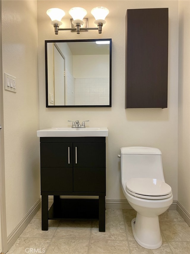 half bathroom featuring toilet, vanity, and baseboards