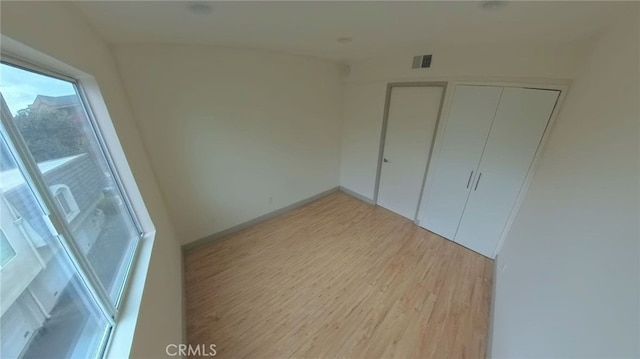 unfurnished bedroom featuring a closet, visible vents, light wood-type flooring, and baseboards