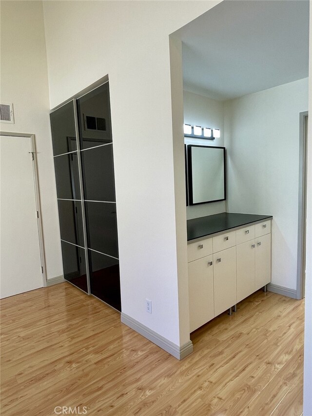 bathroom featuring visible vents, baseboards, wood finished floors, and vanity