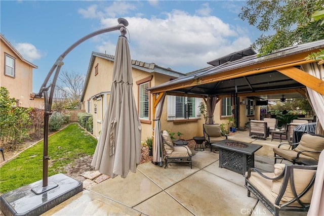 back of property with a gazebo, stucco siding, a patio, and an outdoor fire pit