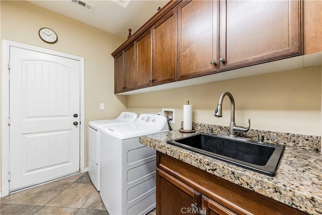 clothes washing area featuring washer and clothes dryer, visible vents, cabinet space, and a sink