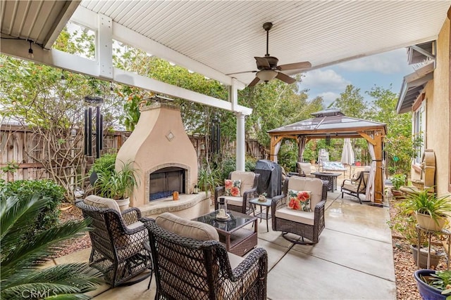 view of patio featuring an outdoor living space with a fireplace, a fenced backyard, a gazebo, a grill, and ceiling fan