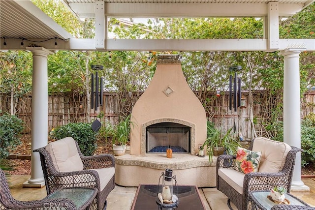 view of patio / terrace with an outdoor living space with a fireplace and fence