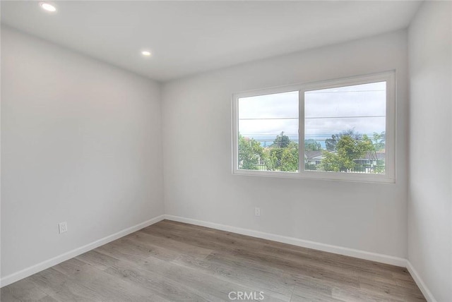 spare room with recessed lighting, light wood-type flooring, and baseboards