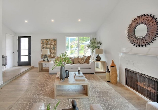 living room featuring vaulted ceiling, light wood finished floors, and a wealth of natural light