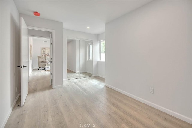 unfurnished bedroom with light wood finished floors, a closet, and baseboards