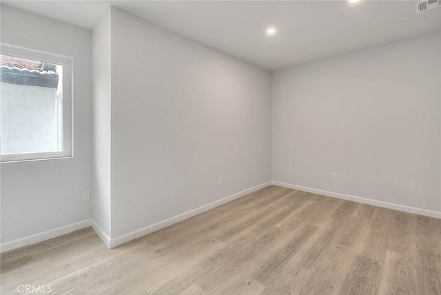 spare room featuring light wood finished floors, visible vents, and a healthy amount of sunlight