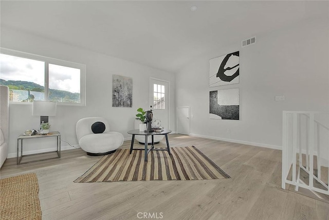 sitting room featuring vaulted ceiling, visible vents, baseboards, and wood finished floors