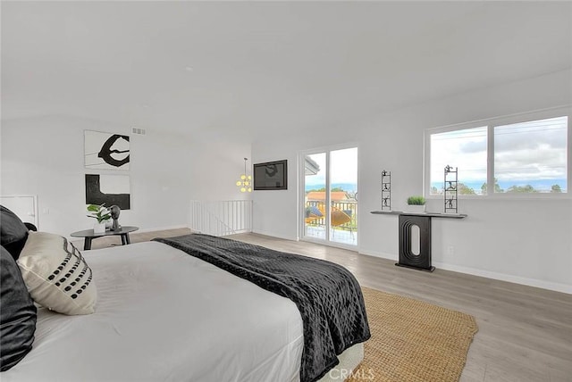 bedroom with baseboards, wood finished floors, a fireplace, and access to outside