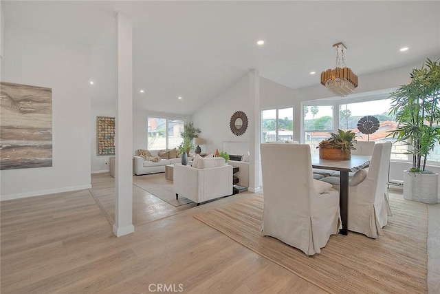 dining space featuring light wood finished floors, baseboards, recessed lighting, a notable chandelier, and high vaulted ceiling