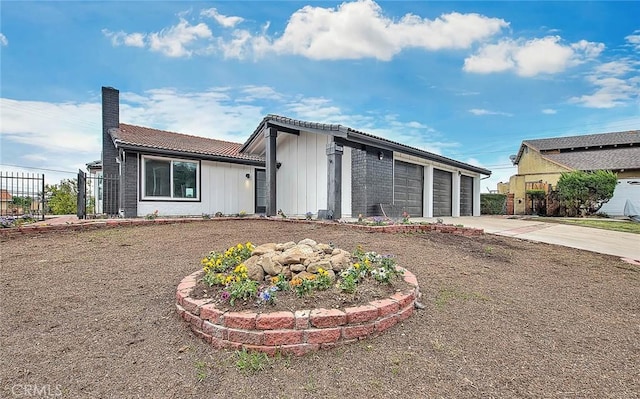 exterior space featuring fence, a chimney, concrete driveway, a garage, and a tile roof