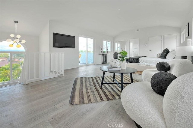 living area with vaulted ceiling, light wood-style flooring, and a chandelier