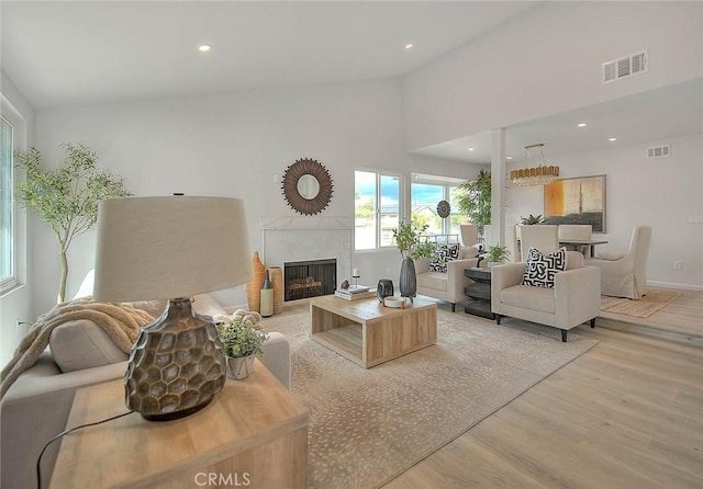 living area with recessed lighting, visible vents, light wood-style floors, and a tiled fireplace