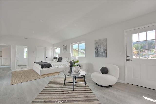 living area with visible vents, baseboards, lofted ceiling, and wood finished floors