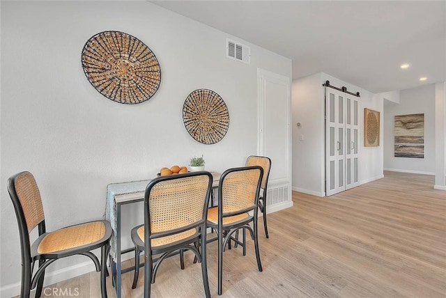 dining space featuring light wood-style flooring, baseboards, and visible vents