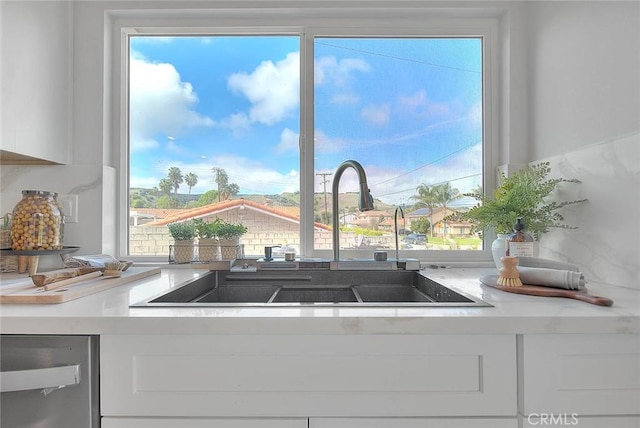 kitchen featuring a sink, white cabinets, and light countertops