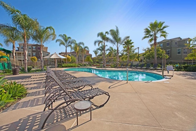 community pool with a patio area and fence