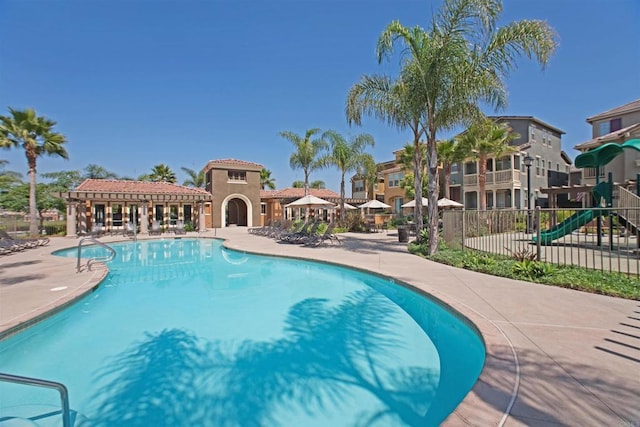 pool featuring playground community, a patio, and fence