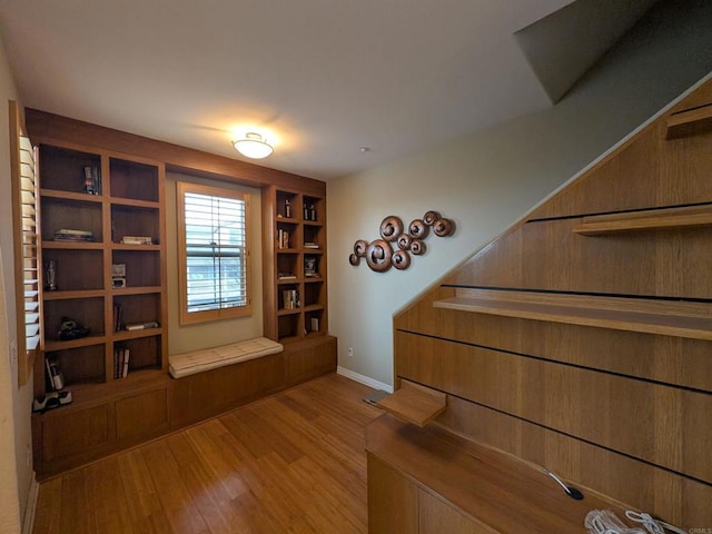 stairway with built in features, baseboards, and wood finished floors